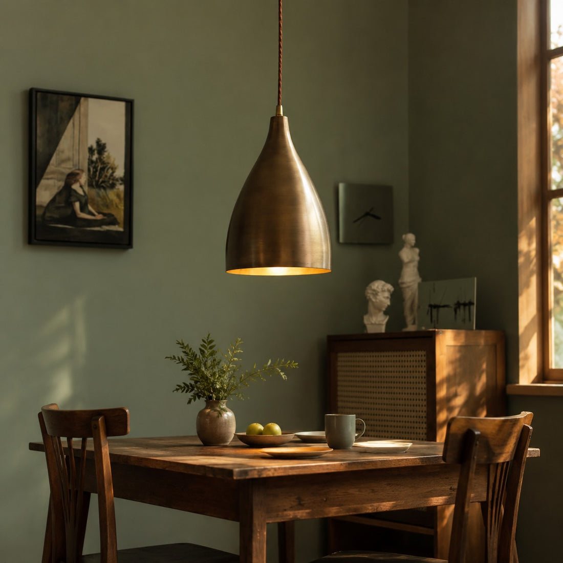 Aged brass pendant light in a green dining room