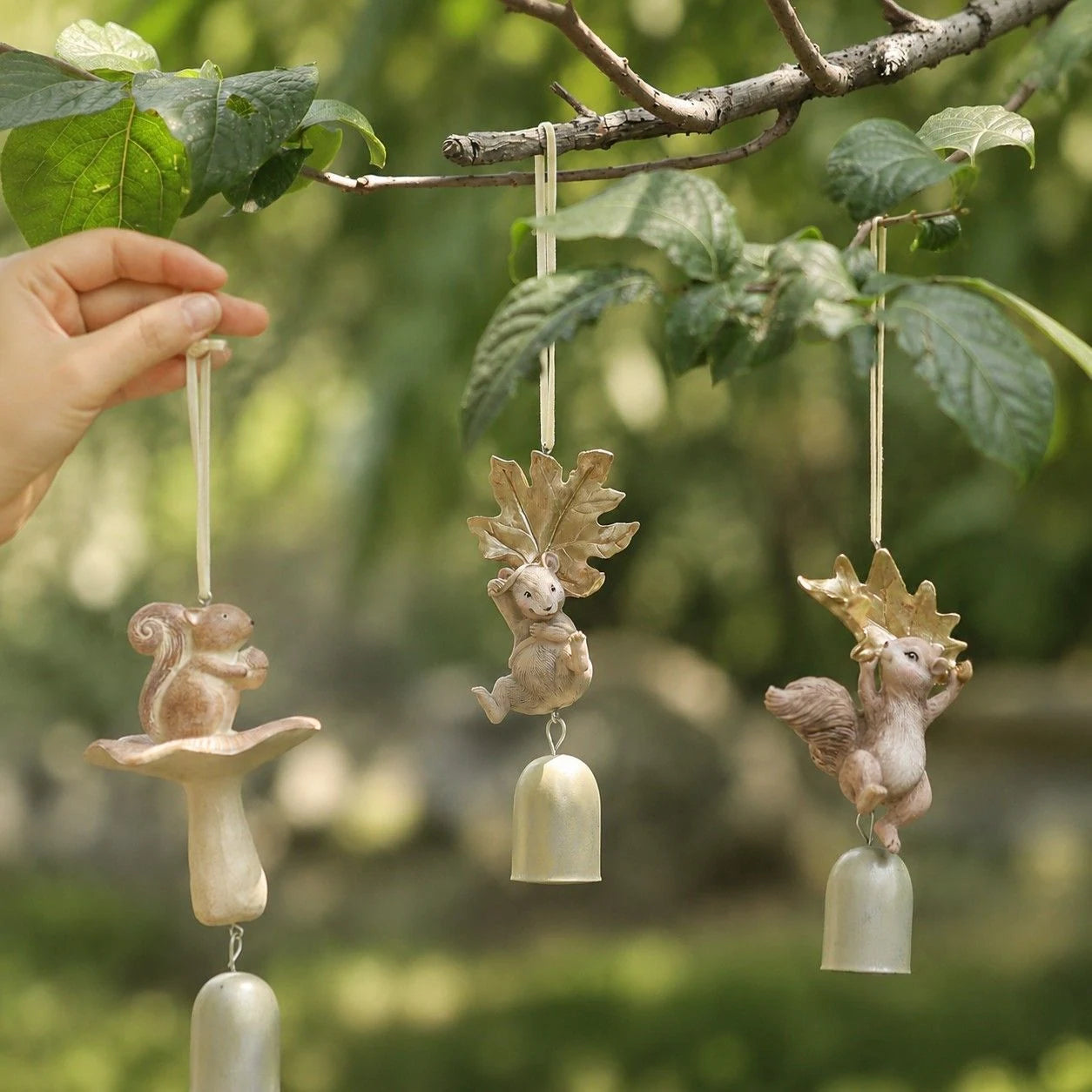 Three warm ivory woodland wind chime styles hanging on a branch