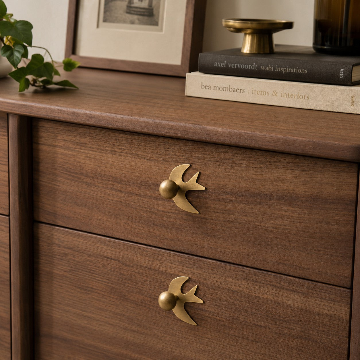 Swallow-shaped brass handles on wood drawers