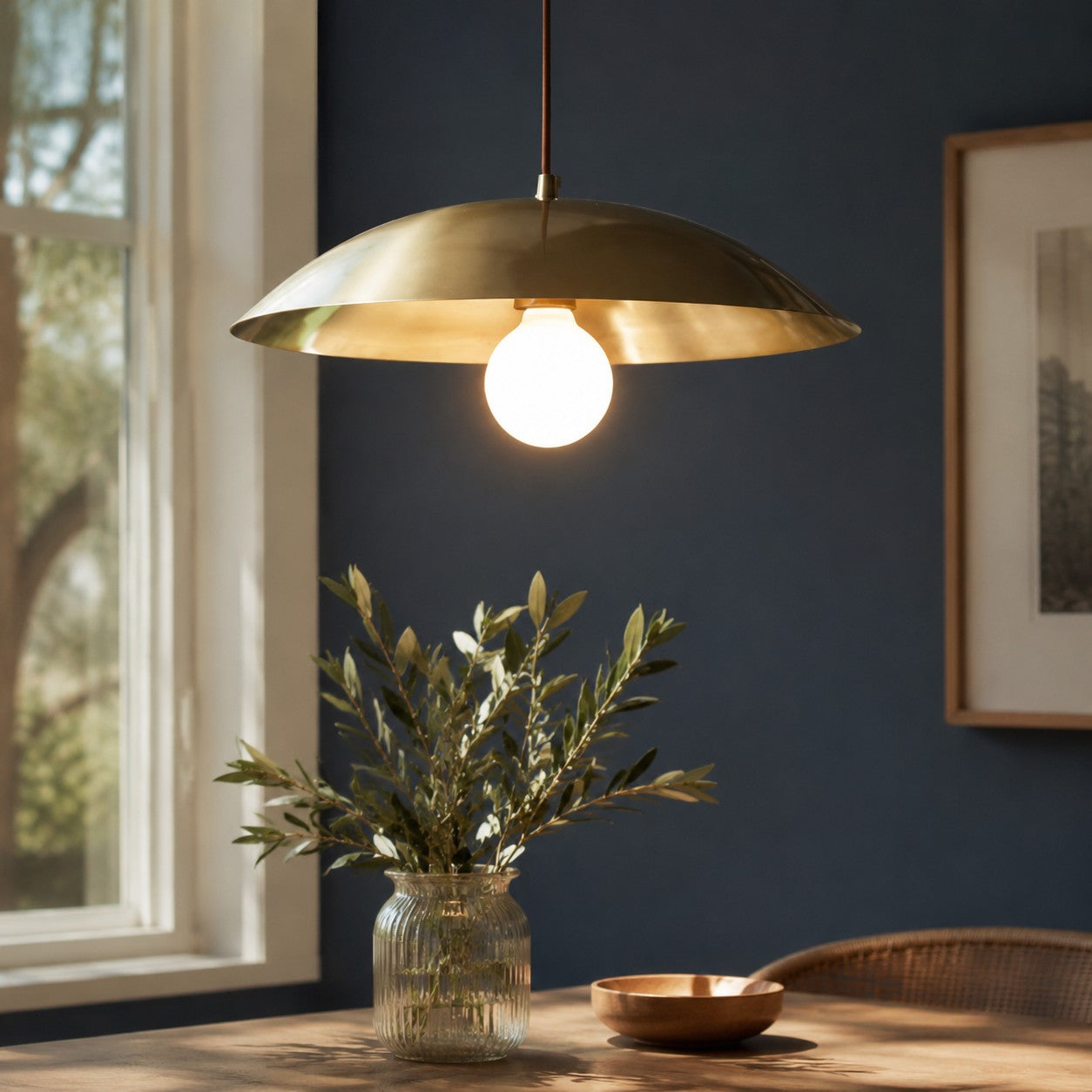 Brushed brass-finish dome pendant light in a dark dining room