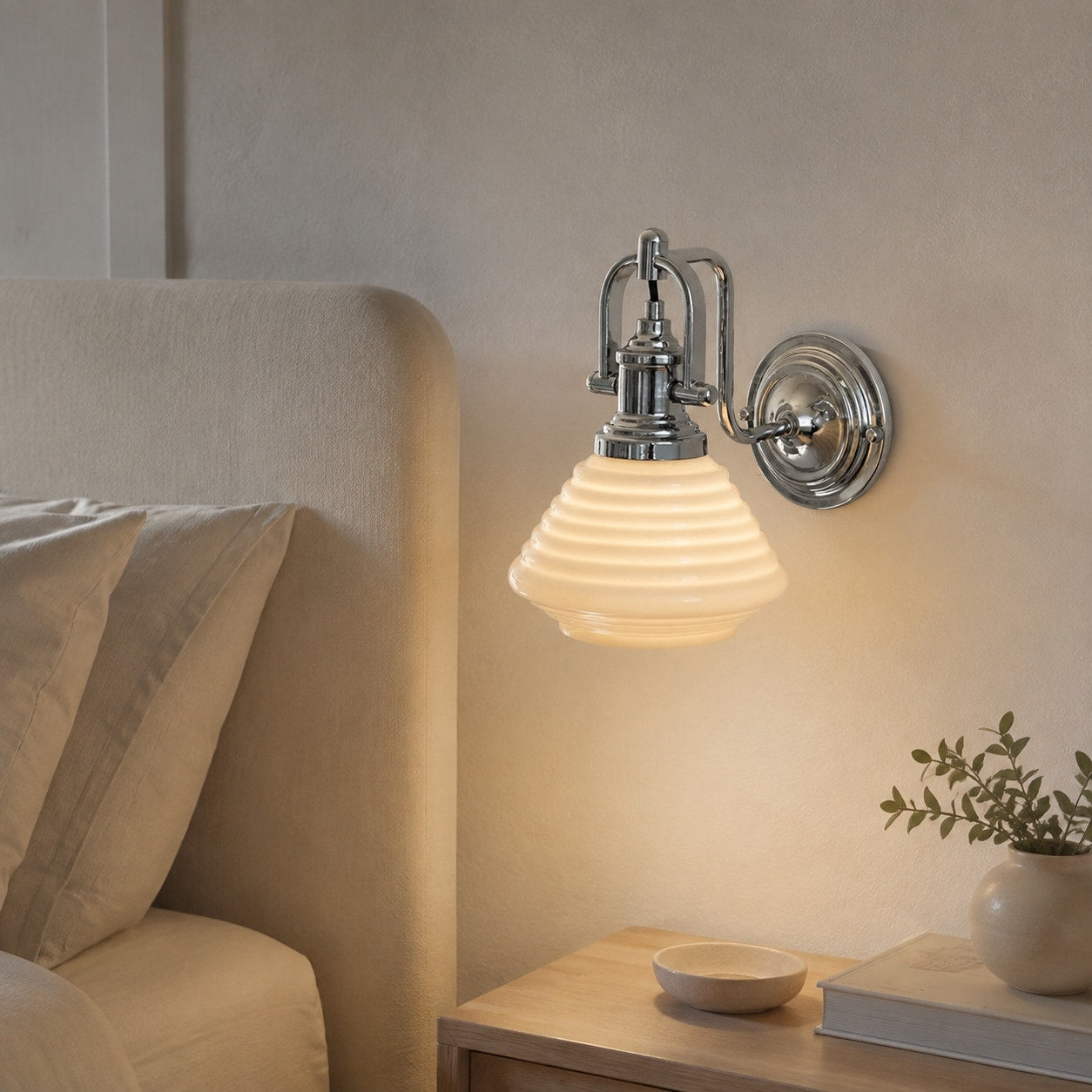 Creamy yellow glass wall sconce beside a bed