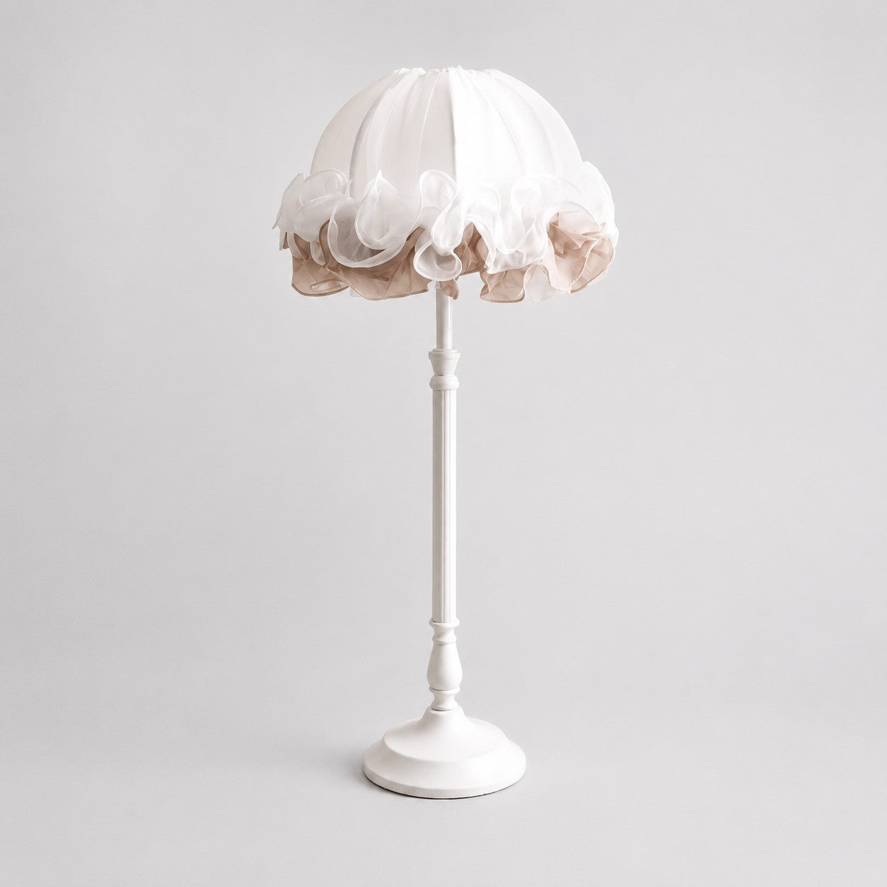 Front view of pure white ruffled fabric table lamp with sculpted metal stem