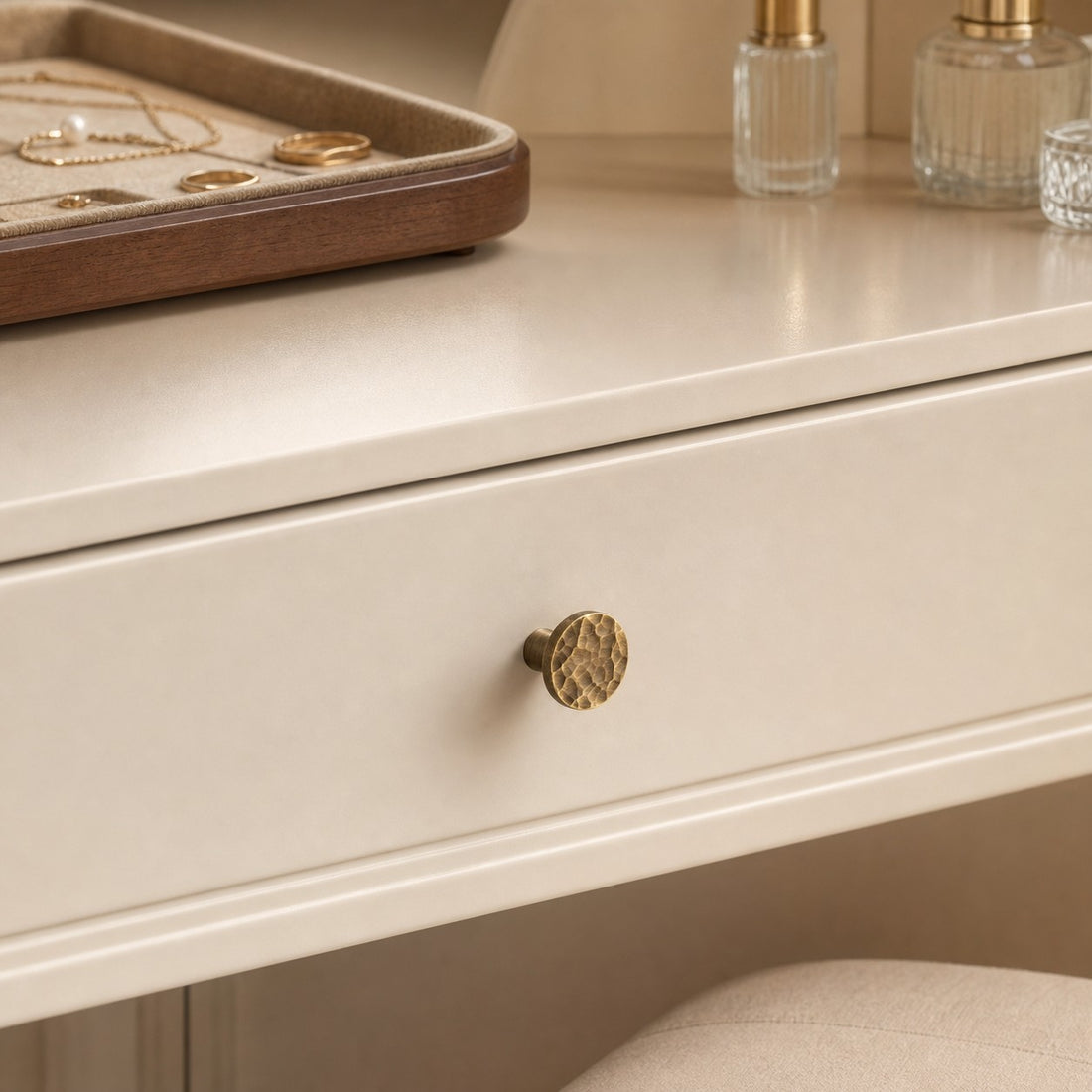 Antique brass cabinet knob installed on a cream drawer