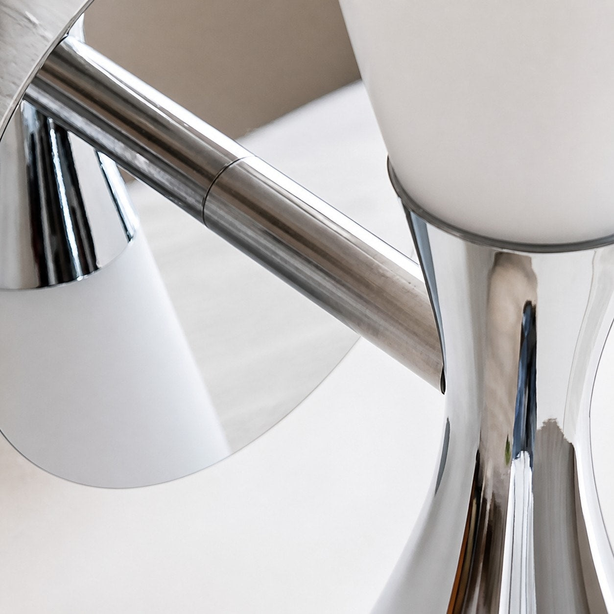 Polished chrome hourglass frame detail on white glass wall lamp