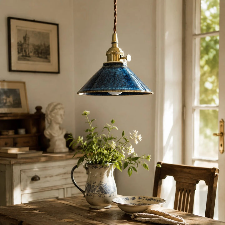 Blue ceramic pendant light above a vintage tea table near a window