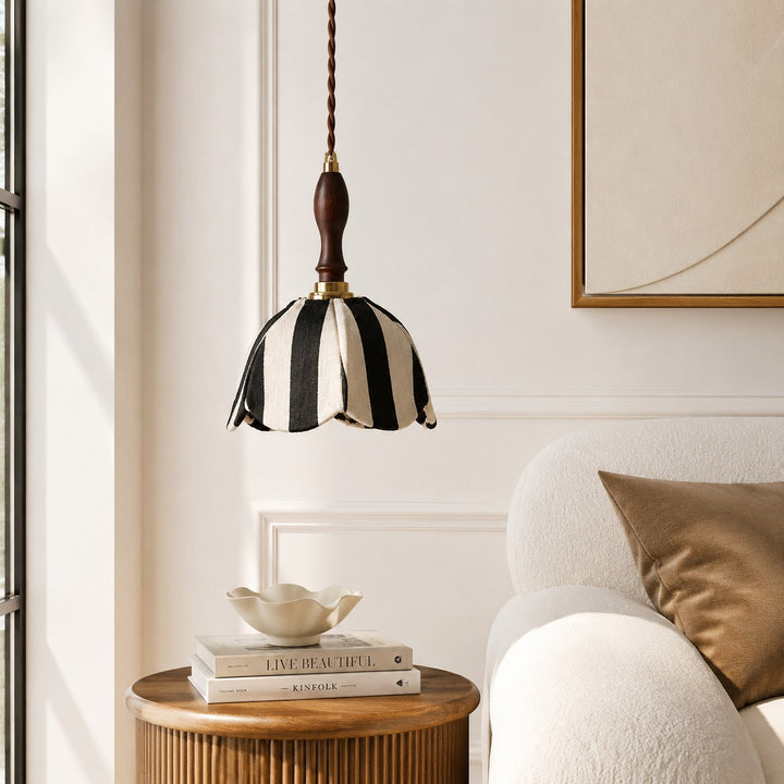 Black and ivory fabric pendant lamp above a side table beside a lounge chair