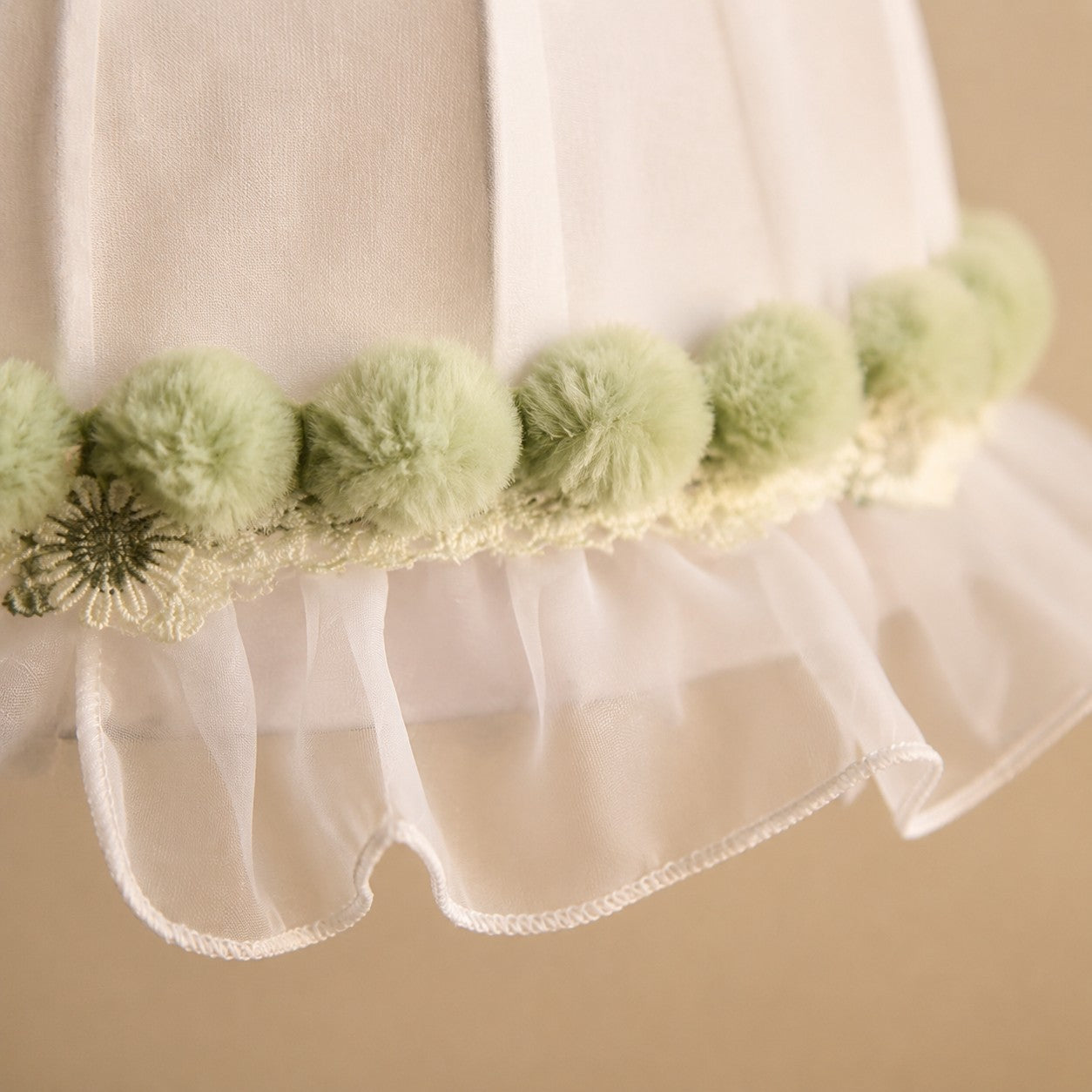 Soft green pom-pom trim and scalloped lace detail