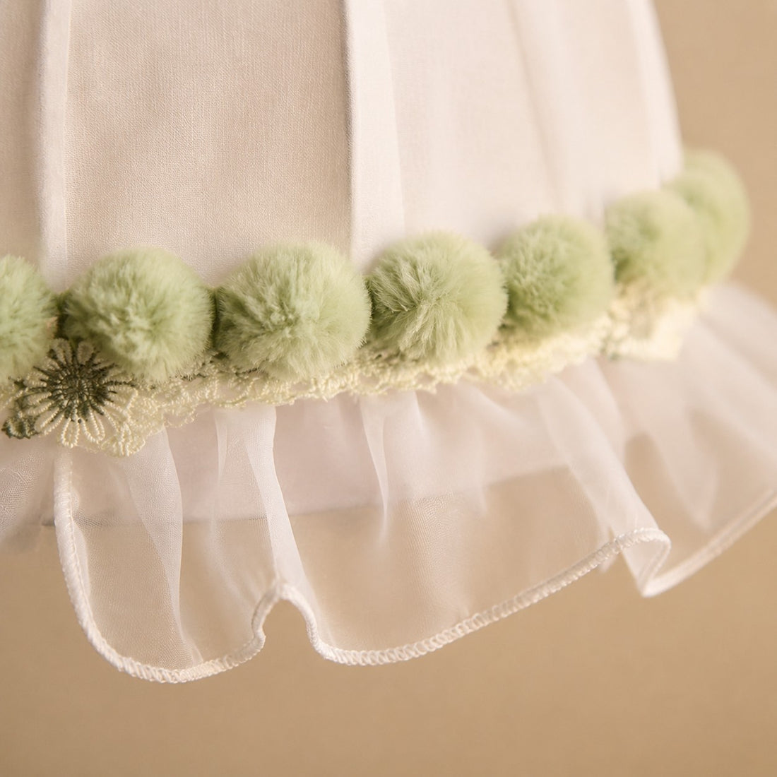 Soft green pom-pom trim and scalloped lace detail