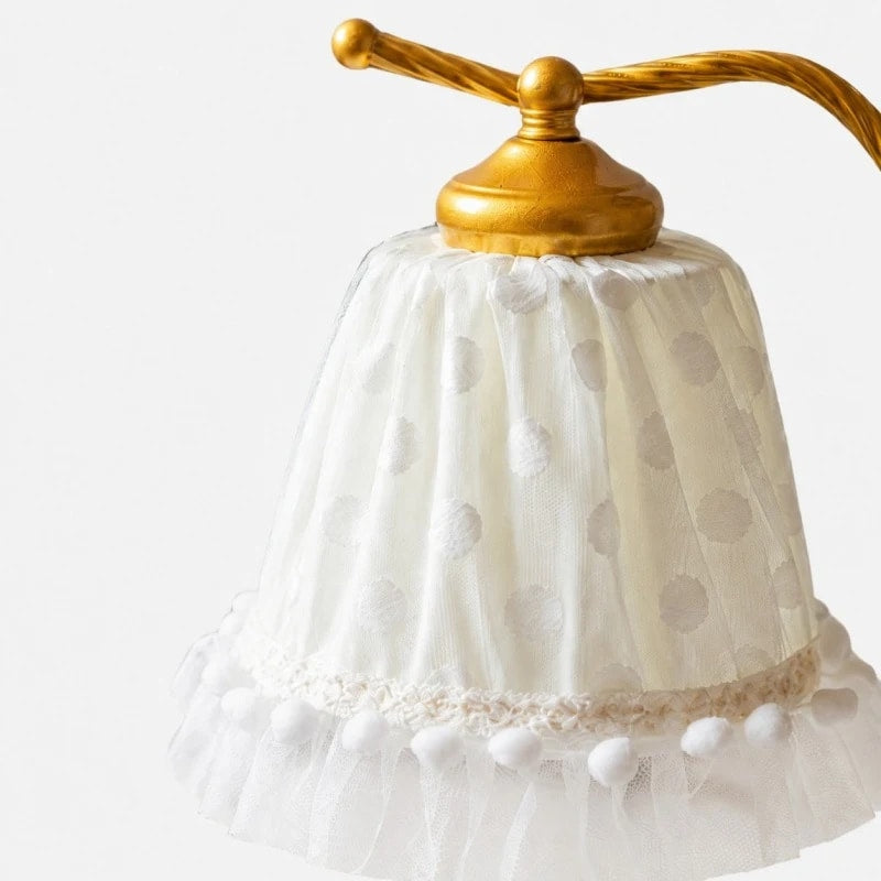 Close view of the white dotted lace shade and gold shade cap