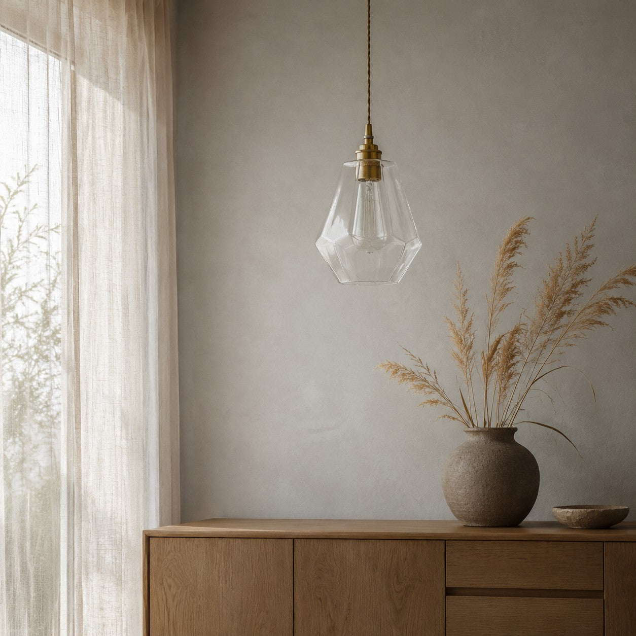 Clear faceted glass pendant light styled beside a curtain and cabinet