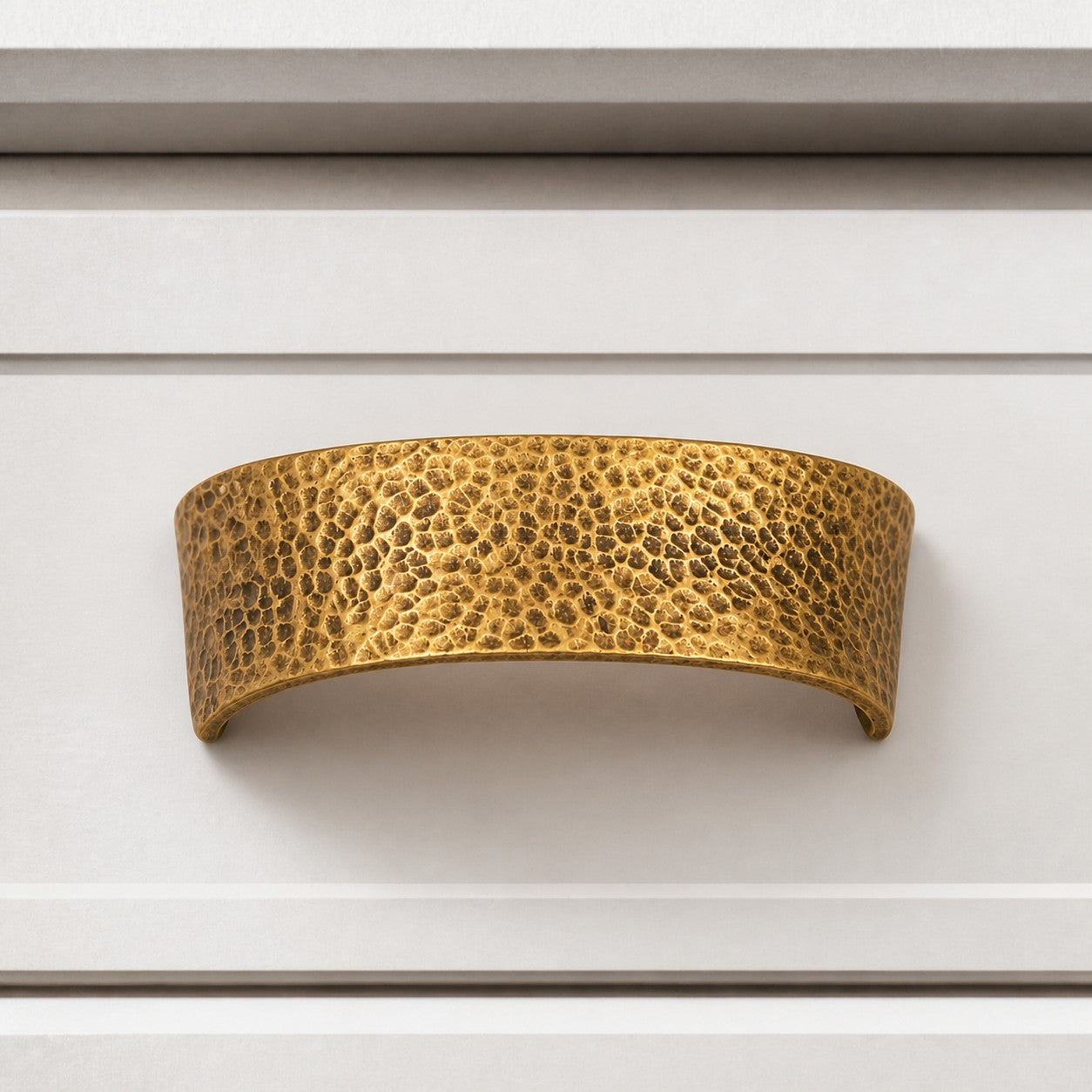 Hammered brass cabinet pull on white drawer front