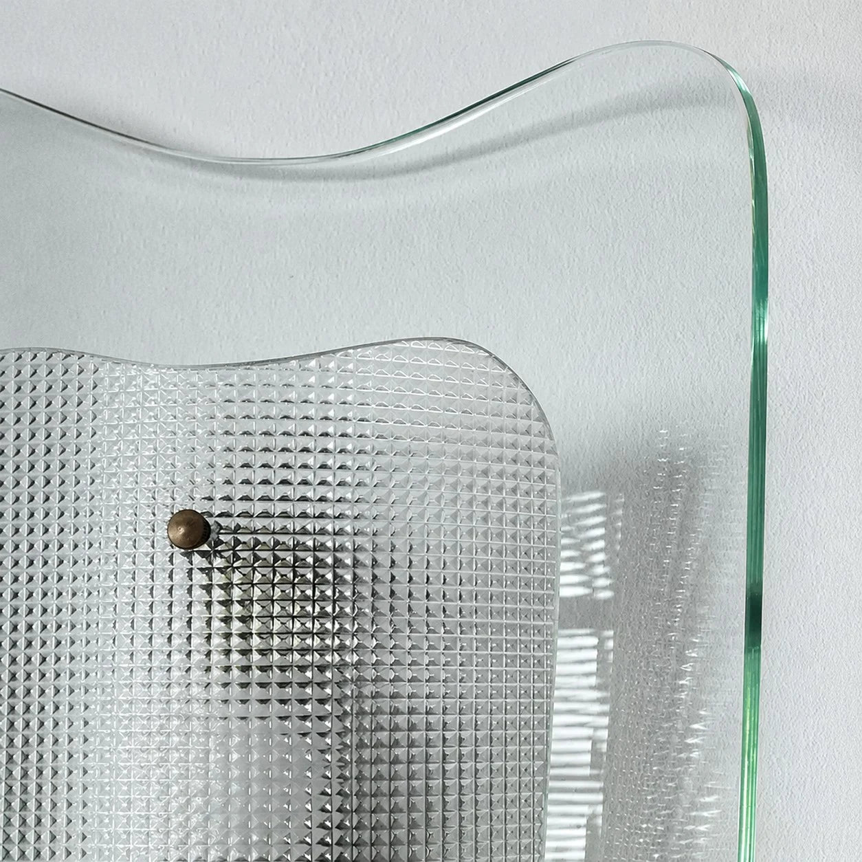Close view of clear glass wall sconce and textured inner shade
