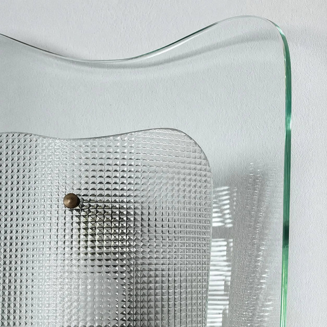 Close view of clear glass wall sconce and textured inner shade