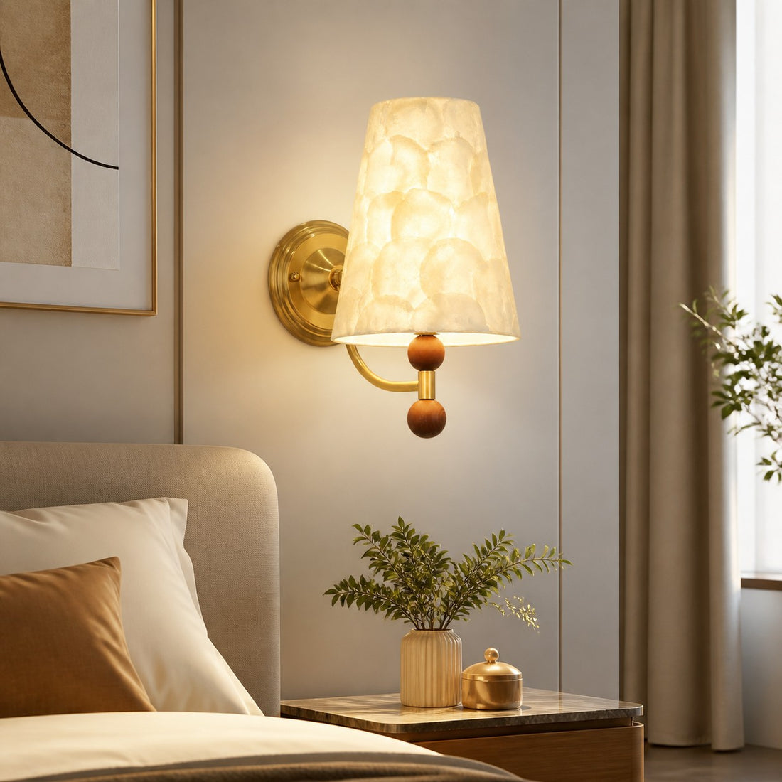 Capiz shell wall sconce installed beside a softly upholstered bed