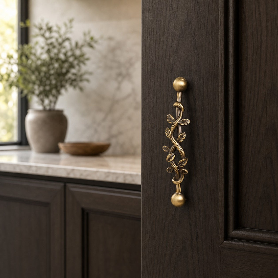 Leaf brass cabinet pull installed on a dark cabinet door