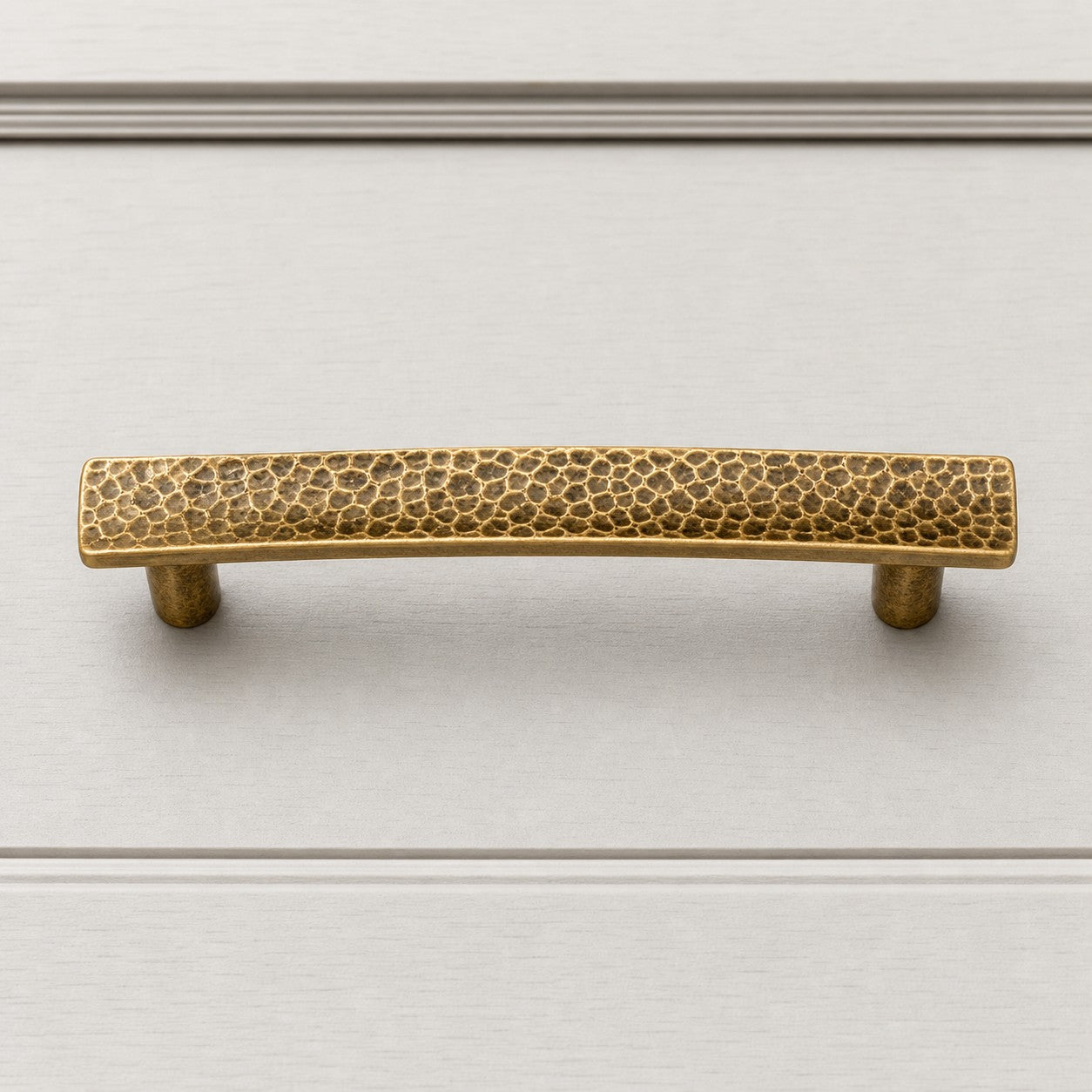 Hammered brass cabinet pull on white cabinet drawer