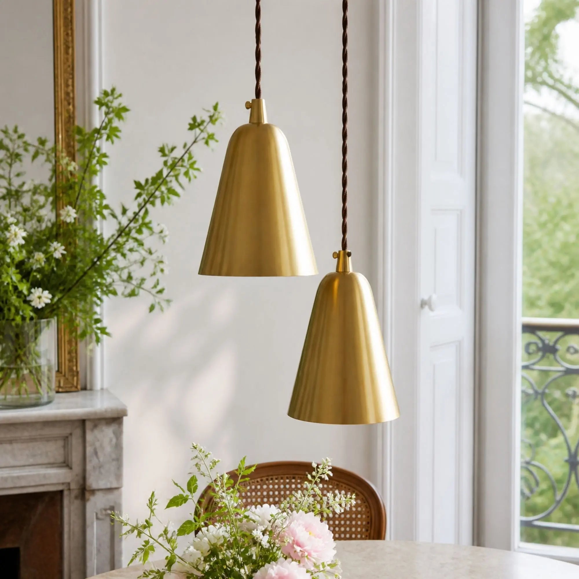 Pair of straight natural brass pendant lights by a window