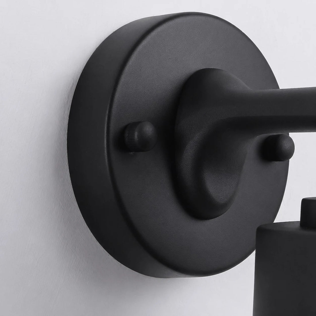 Close view of the black round wall plate and metal arm