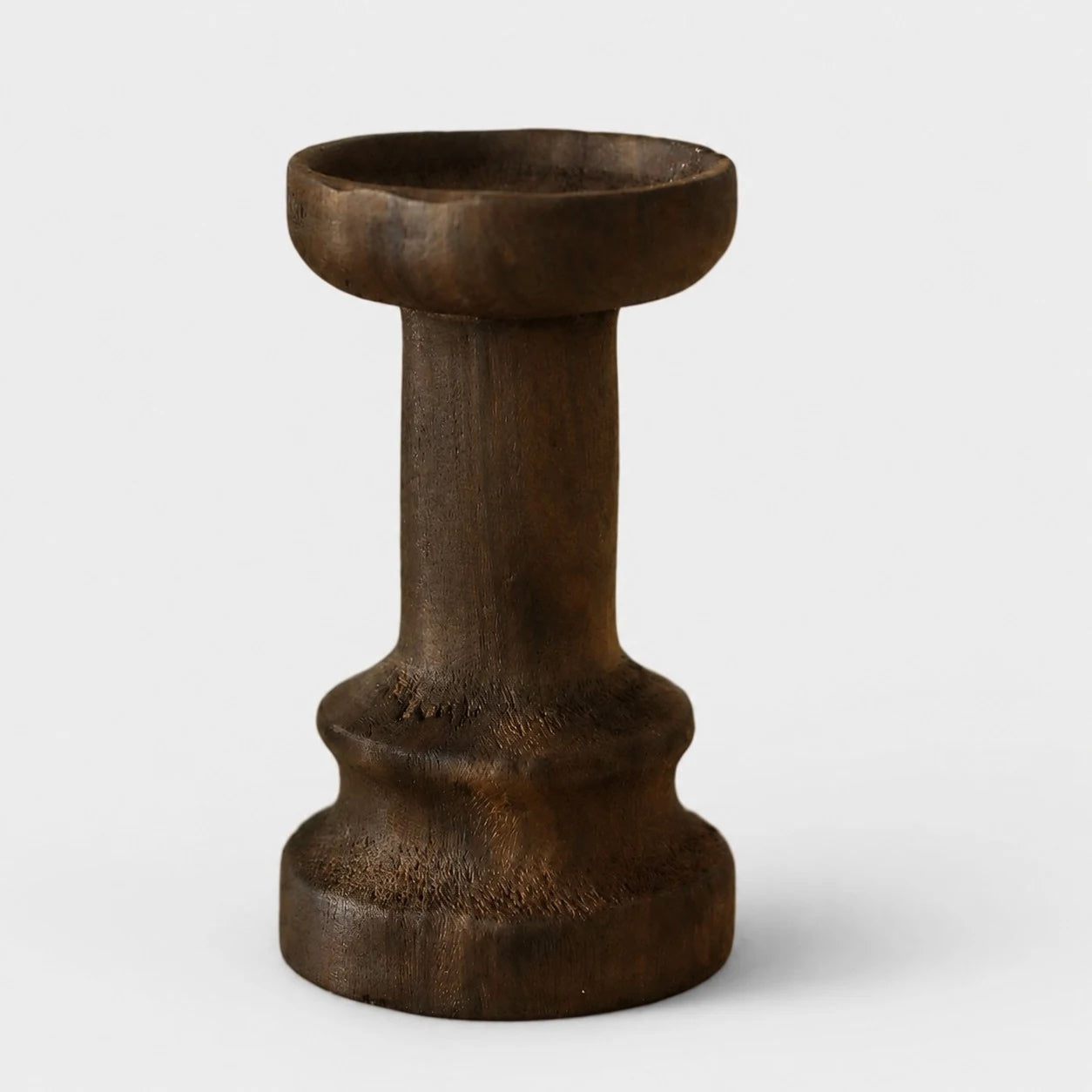 Tall dark solid wood candle holder on a neutral background