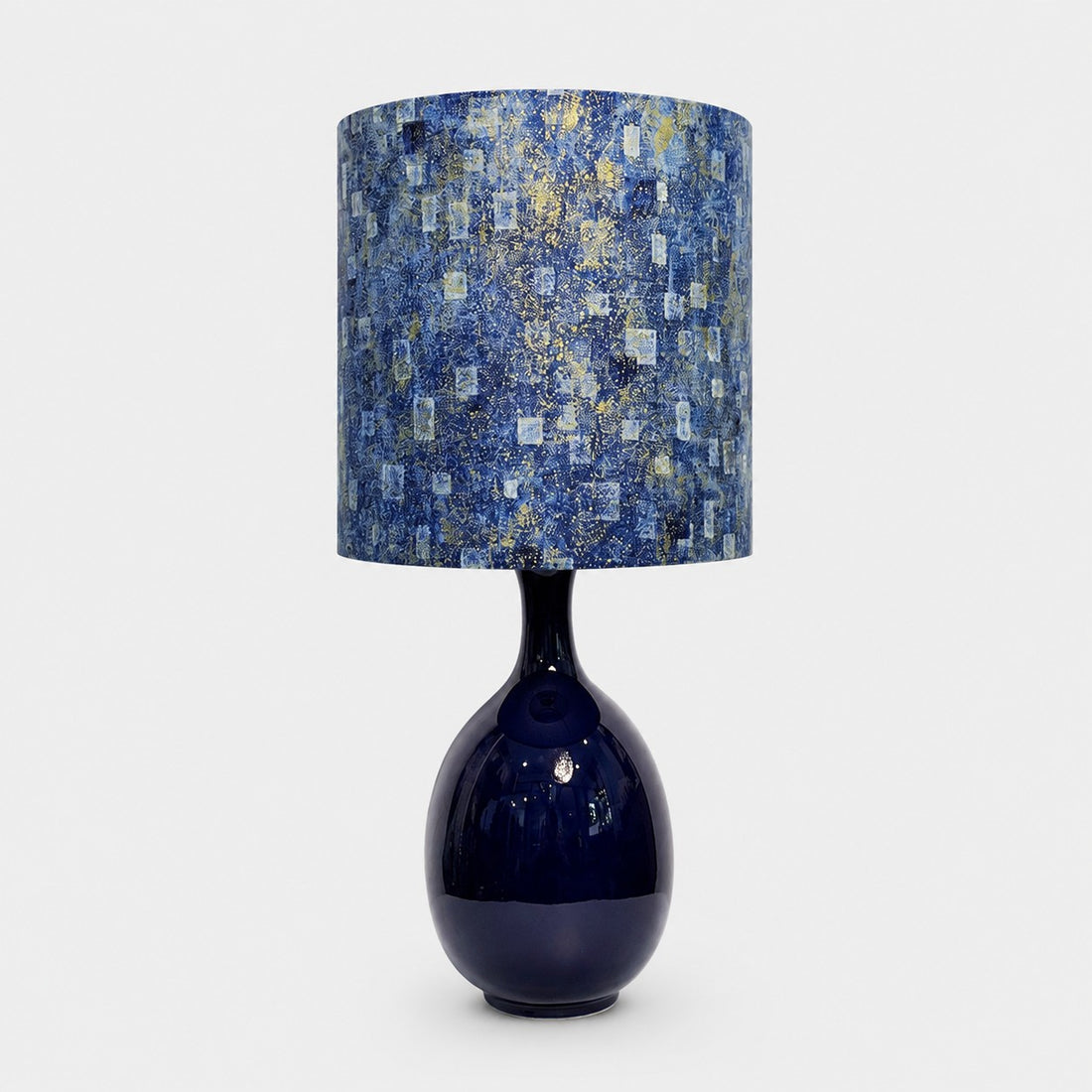 Blue gold patterned fabric ceramic table lamp on plain background