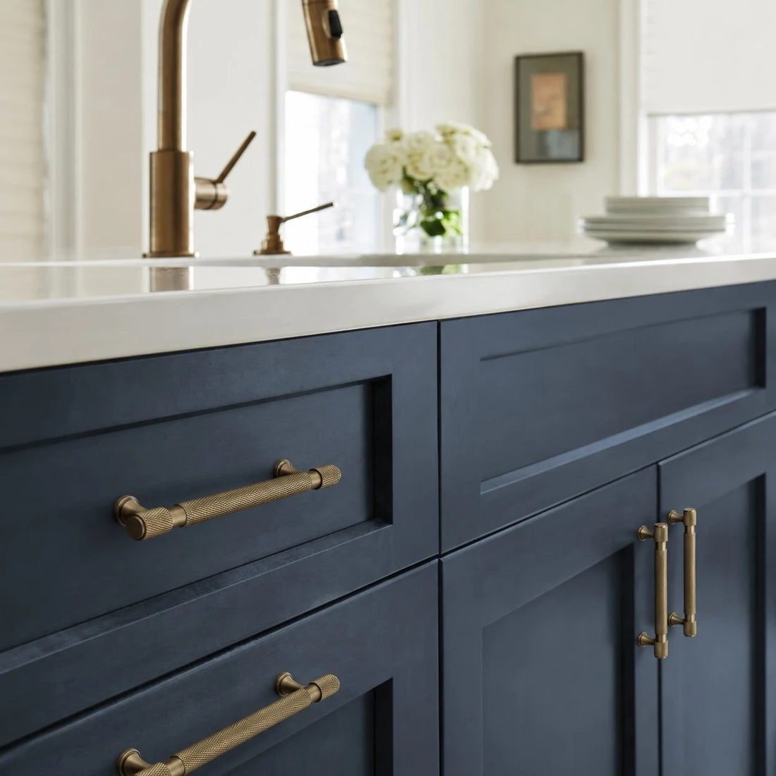 Antique brass pulls installed on blue kitchen cabinetry