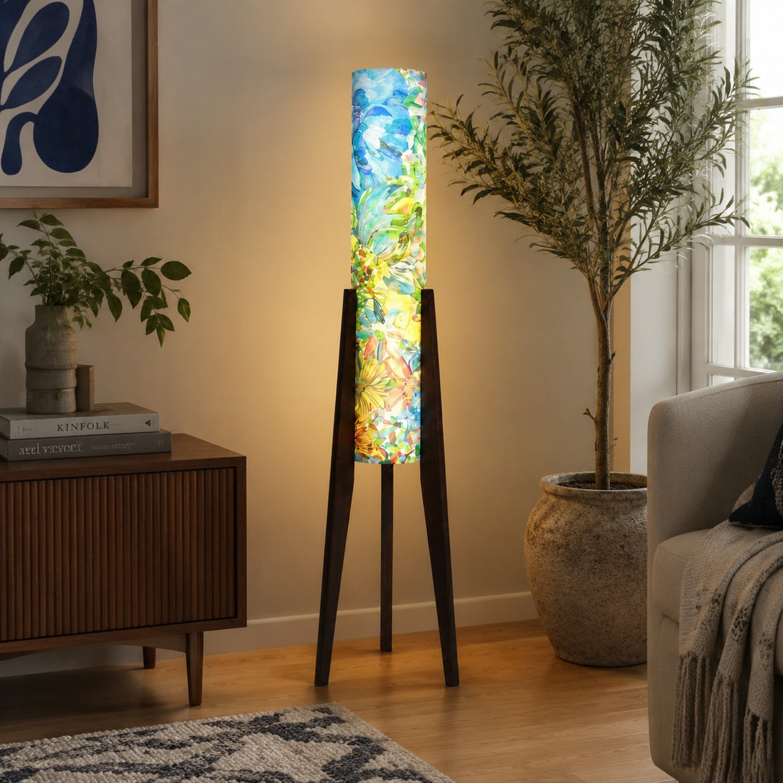 Blue botanical tripod floor lamp illuminating a quiet interior