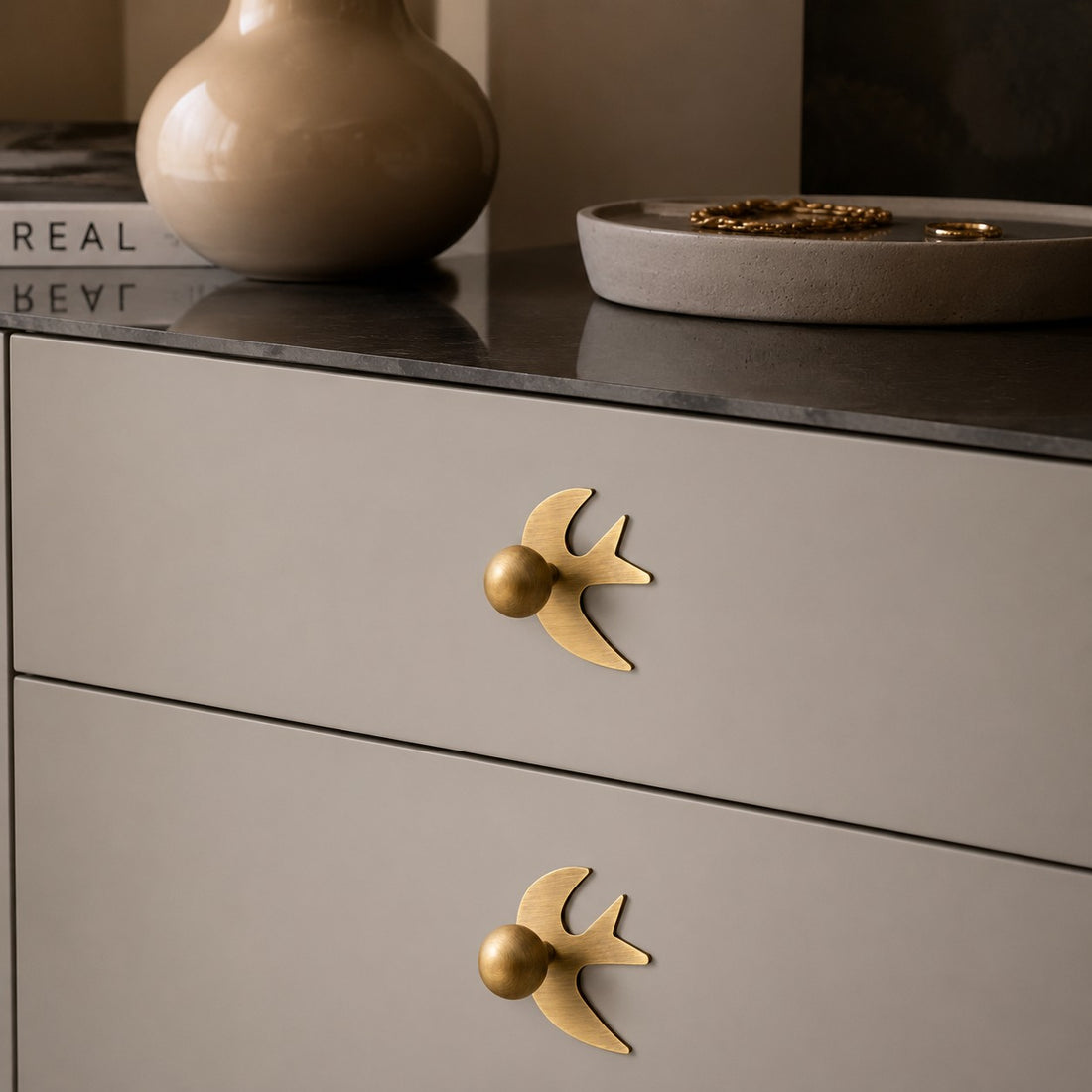 Antique brass swallow handles on a neutral dresser
