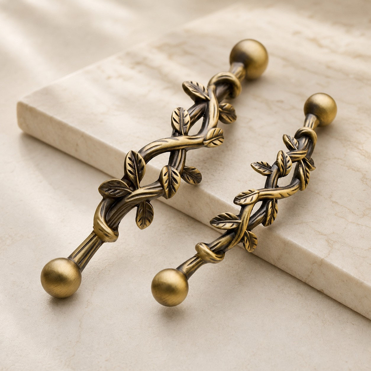 Two solid brass leaf cabinet pulls on a warm stone surface