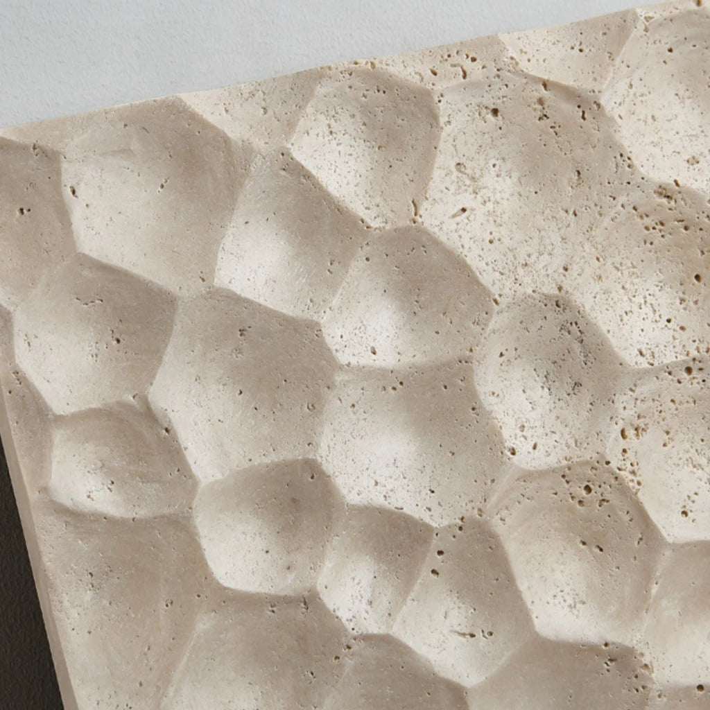 Carved stone relief face detail on a square travertine wall lamp