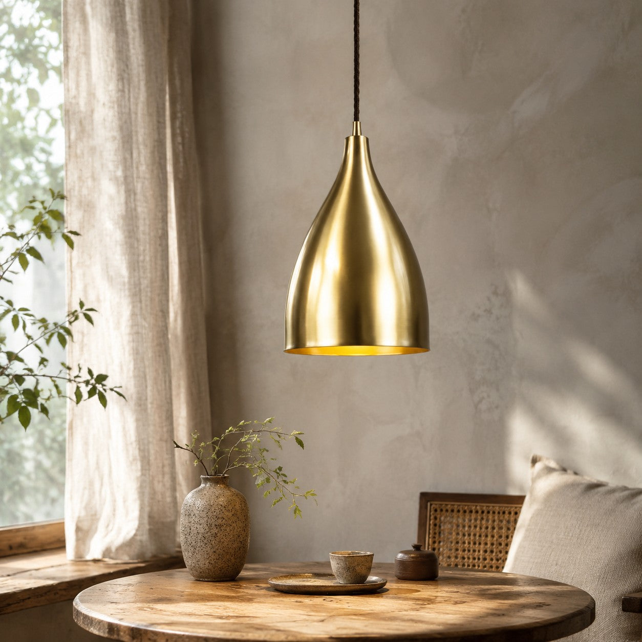 Bright brass pendant light above a round table near a window