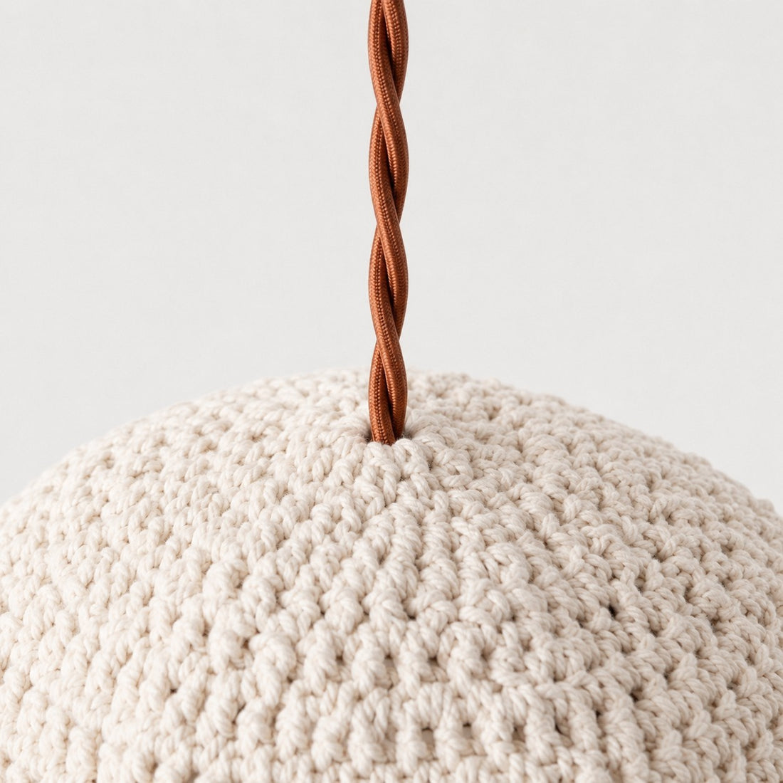 Close-up of twisted brown pendant cord entering the ivory handwoven shade