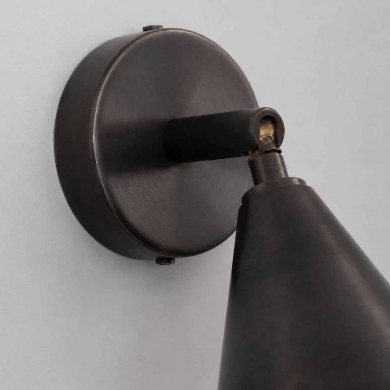 Round wall plate and adjustable arm detail on matte black wall light