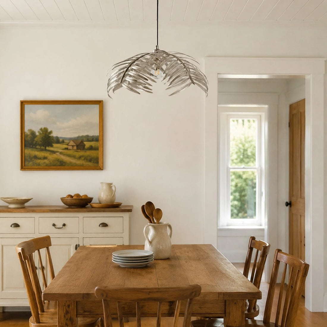 Silver palm leaf chandelier above a rustic dining table