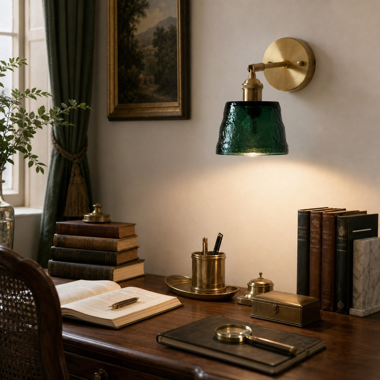 Green brass glass wall sconce above a writing desk