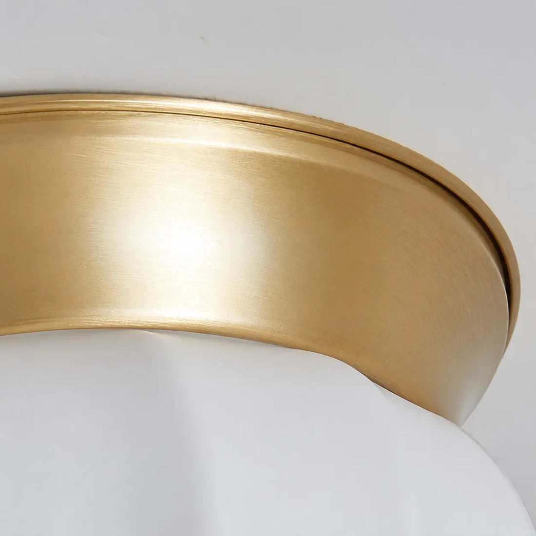 Close view of the brushed brass canopy and opal glass shade