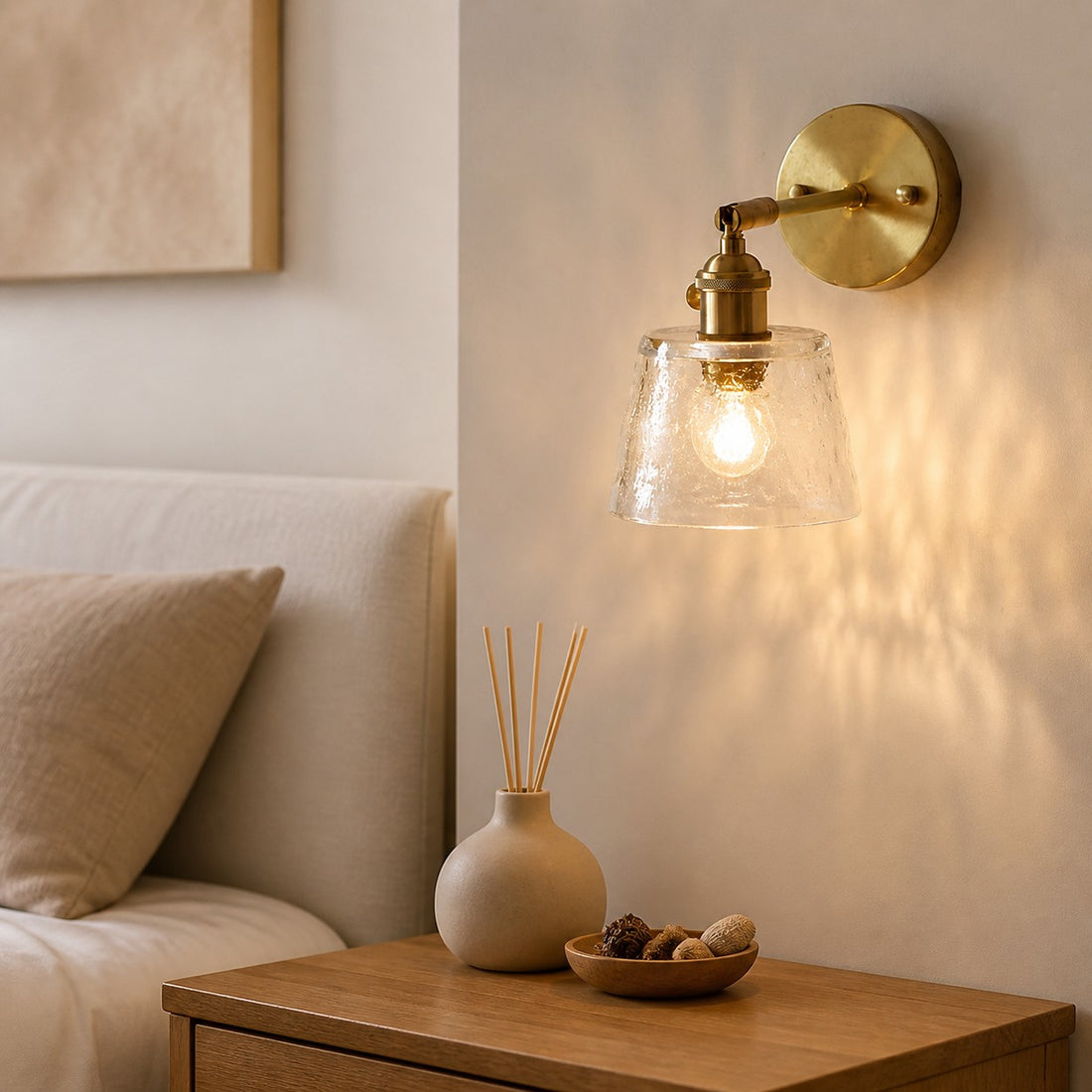Clear brass glass wall sconce beside a bed