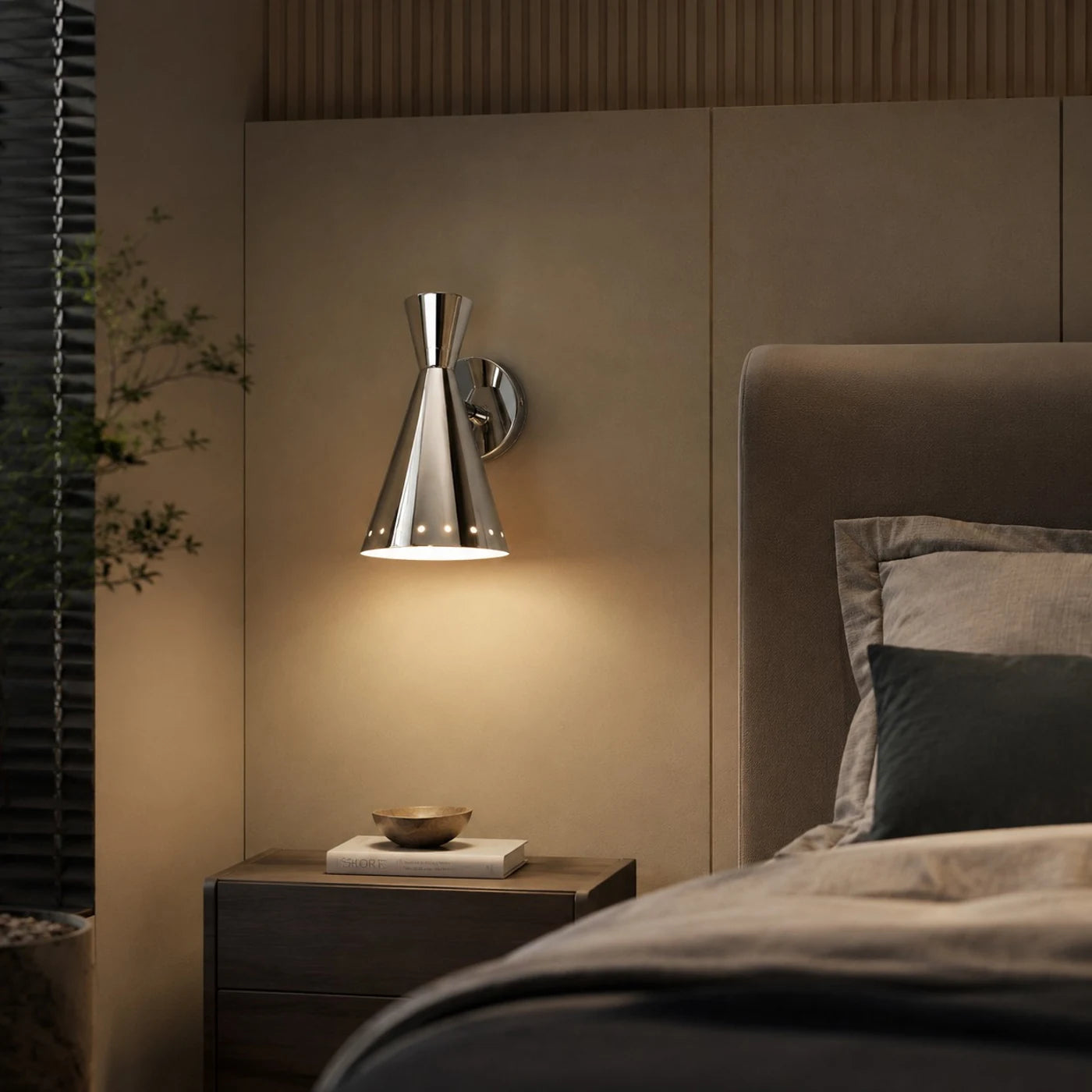 Polished cone wall sconce installed beside a bed