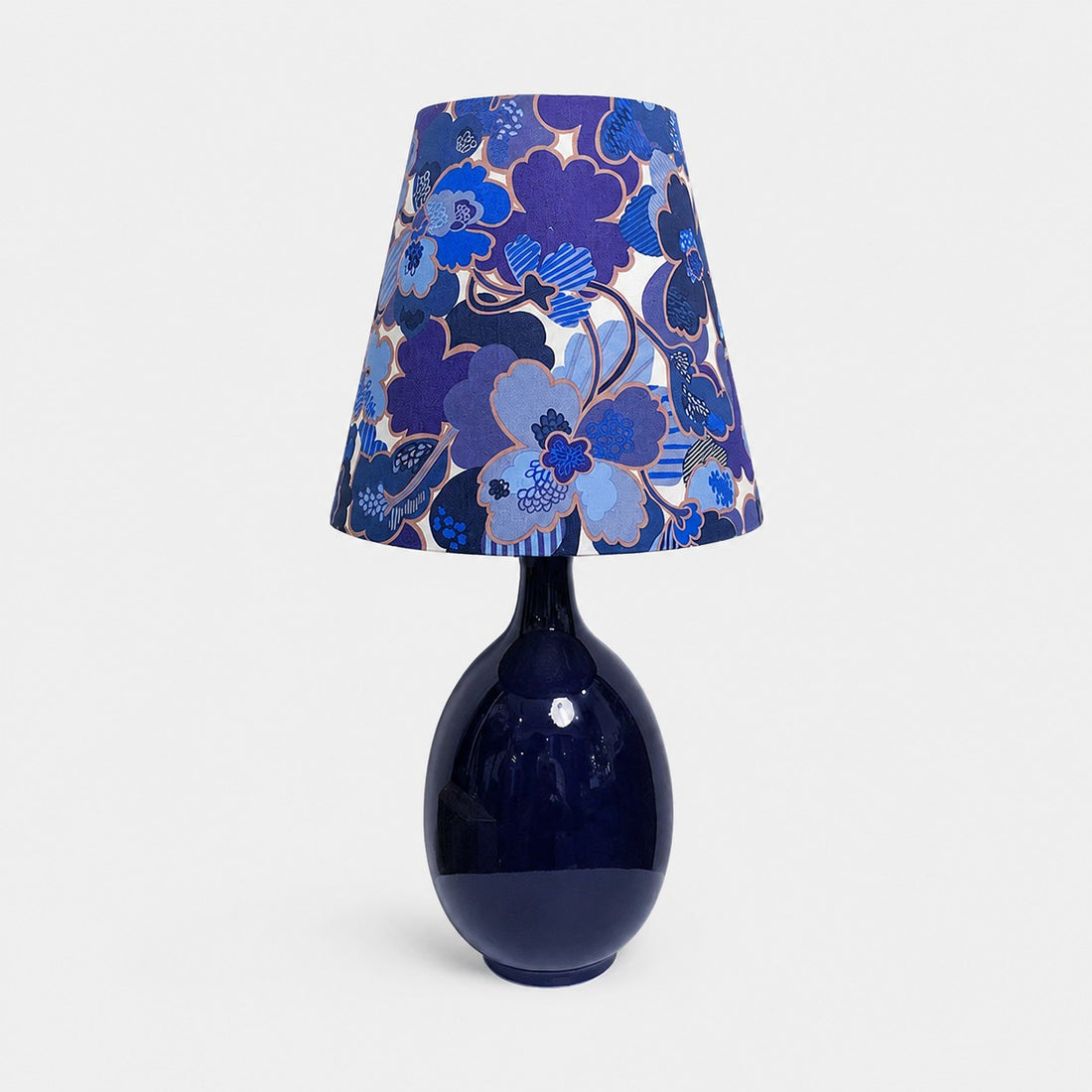 Blue floral fabric ceramic table lamp on plain background