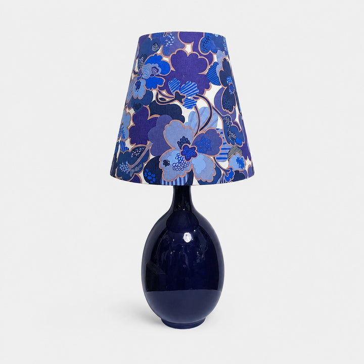Blue floral fabric ceramic table lamp on plain background