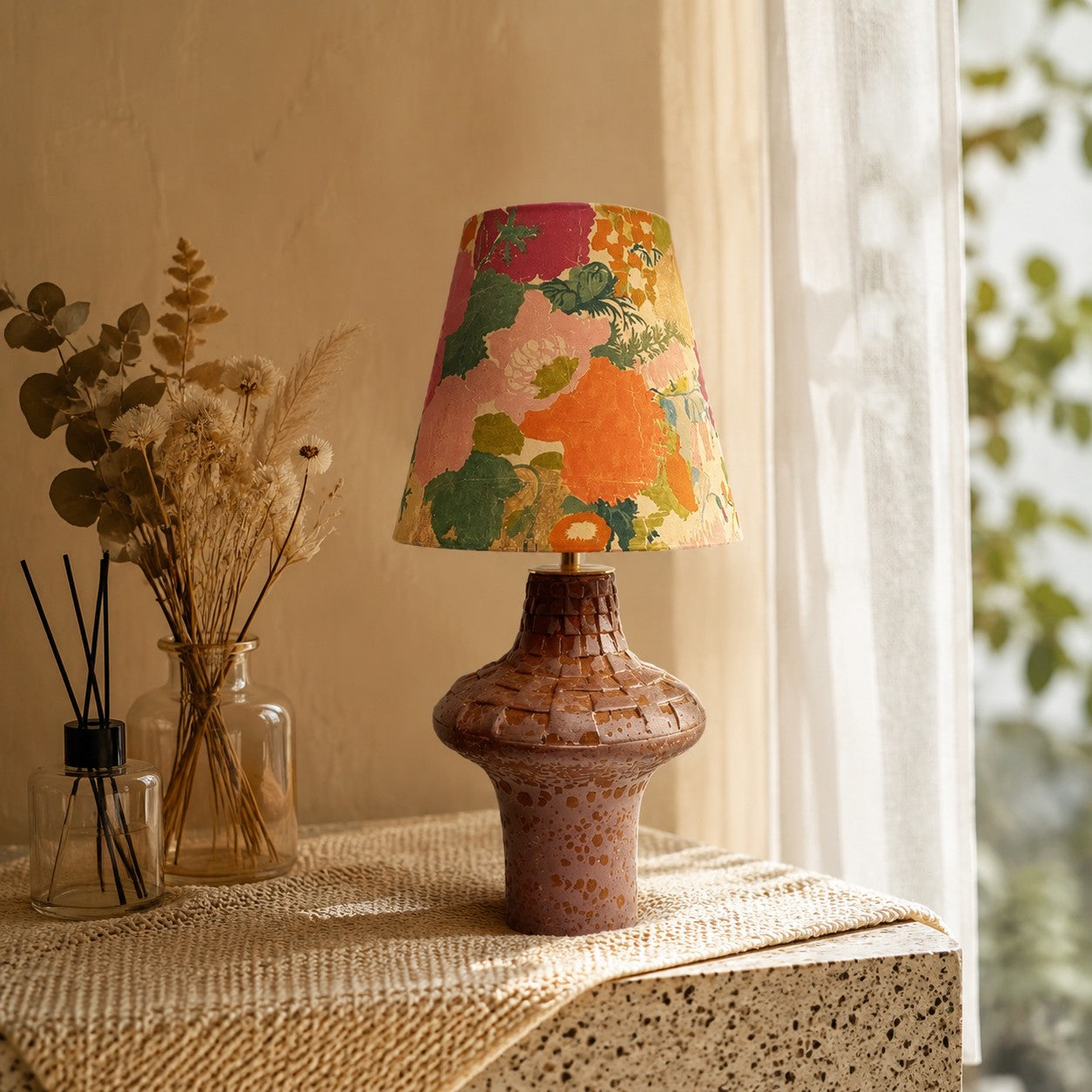 Orange floral ceramic table lamp on a textured console table