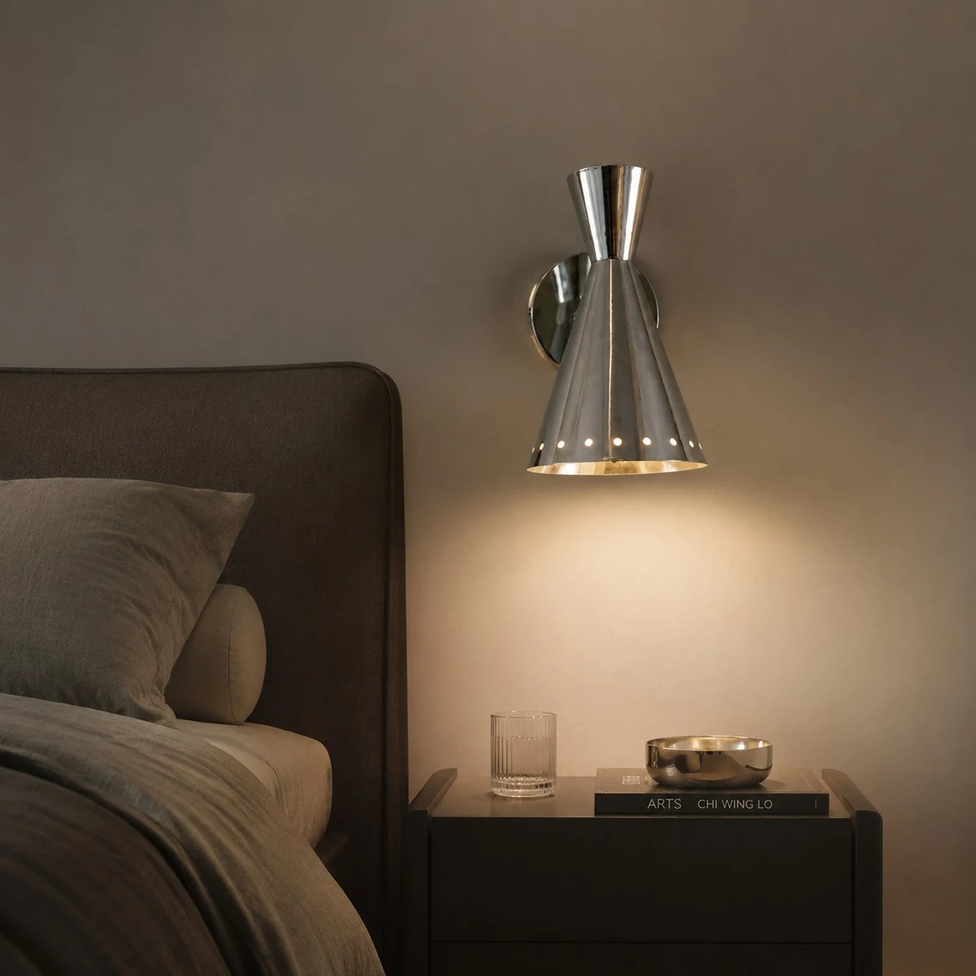 Warm bedside lighting from a polished metal wall sconce