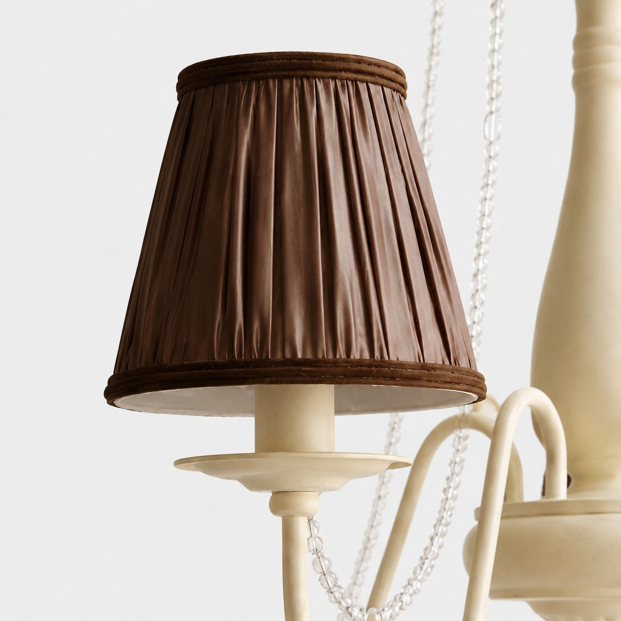Close-up of pleated brown fabric chandelier shade with wrapped trim